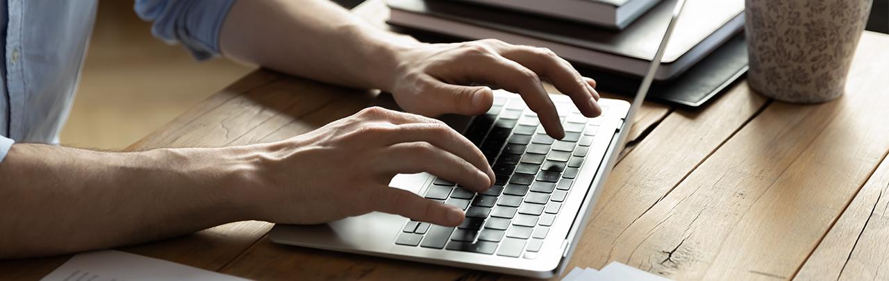 Closeup of a person's hands typing on a computer