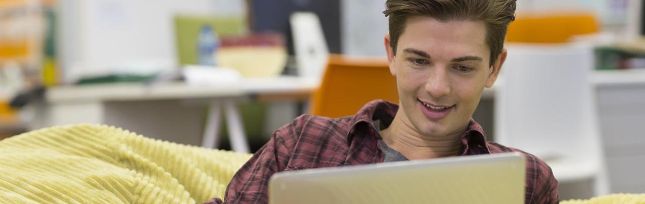 Young man lounging comfortably using a laptop computer