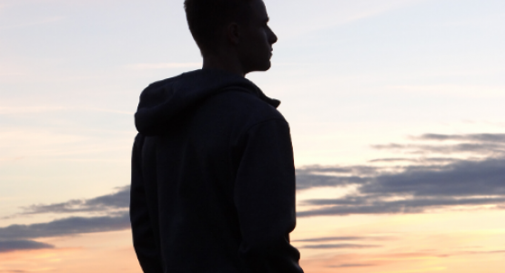 Silhouette of a man outside looking off into the sunset