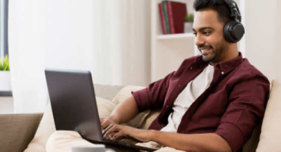 Man wearing headphones using a laptop